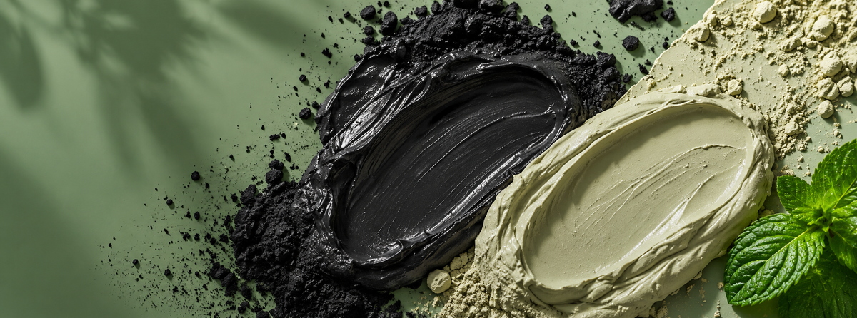 Contrasting black and pale green clay mask textures with scattered clay powder and fresh green leaves.