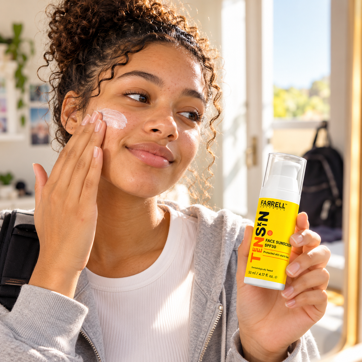 Teenage girl applying Farrell Naturals Face Sunscreen SPF30 to her cheek in a bright room.