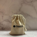 Beige drawstring bag with 'FARRELL' logo on a marble surface