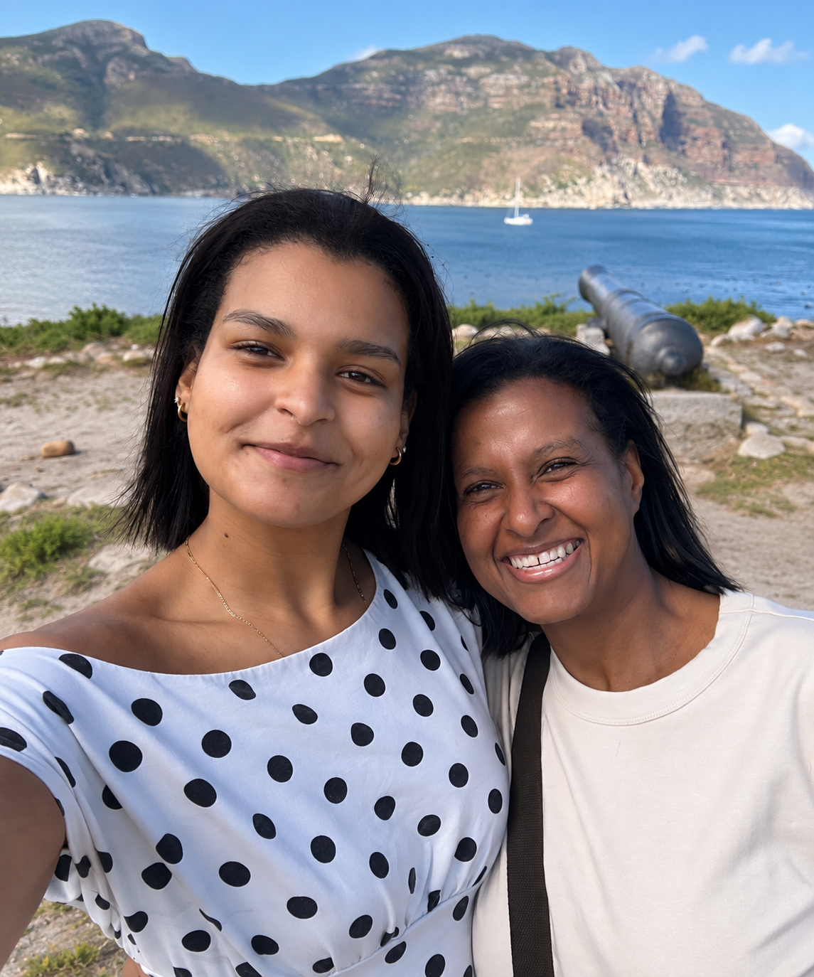 Farrell Naturals founder Nieshell and her daughter Farrell smiling together beside the ocean with mountains in the background.